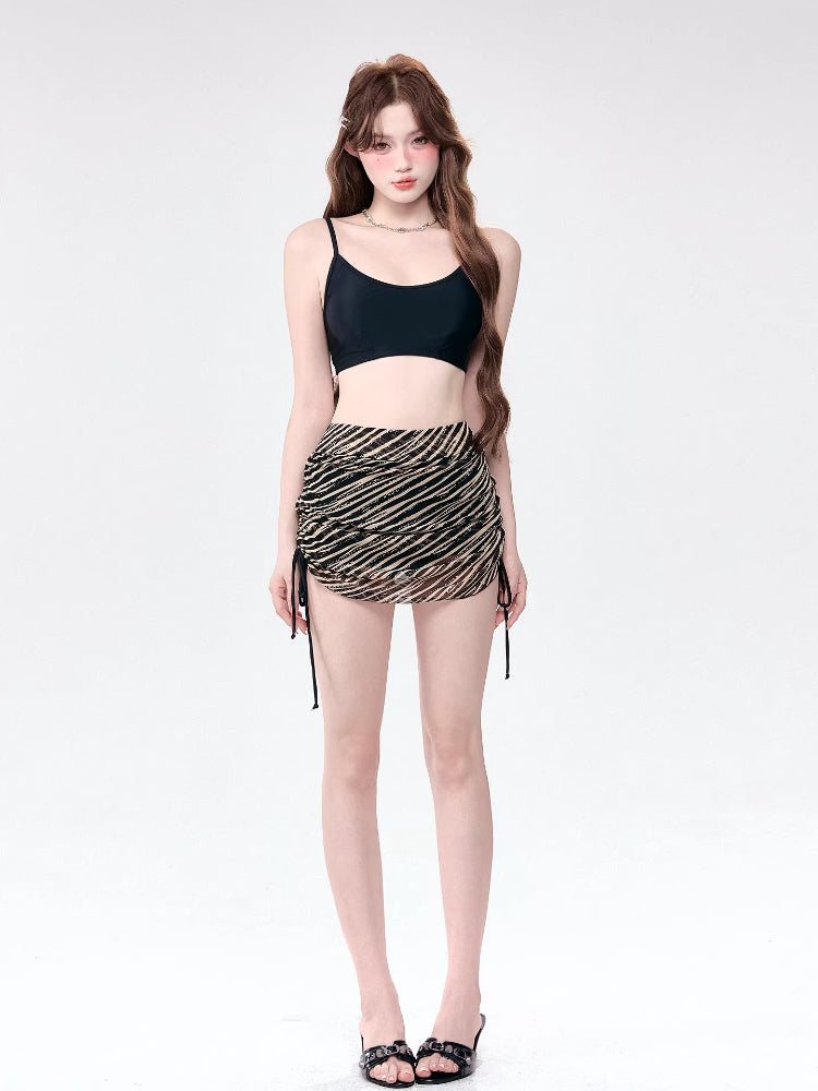Woman wearing a black camisole and a striped ruched mini skirt.