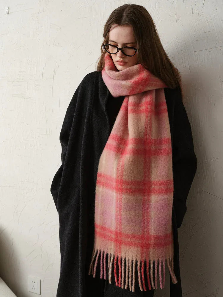 Woman wearing a black coat and a pink plaid scarf.