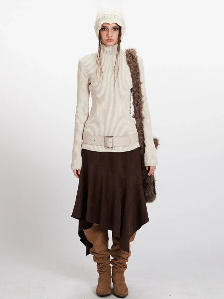 Model wearing a cream ribbed turtleneck sweater, brown asymmetrical hem skirt, cream belt, brown boots, cream knit beanie, and a brown faux fur shoulder bag, front view. Main image