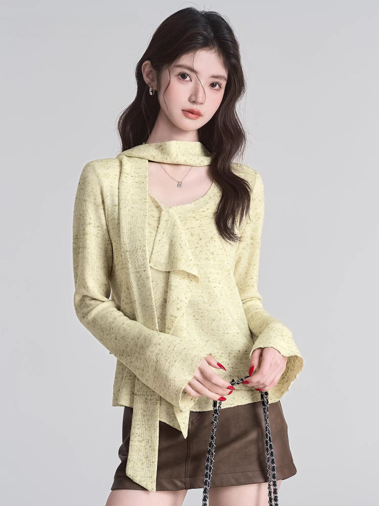 Close-up of a woman wearing a light yellow textured knit top with a draped neckline and ruffle detail.