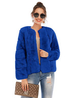 Woman wearing a royal blue faux fur jacket over a light-colored top and ripped jeans, holding a gold clutch.