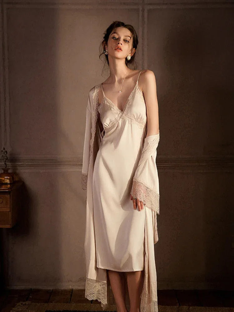 Full-length view of a woman in a cream satin slip dress with lace trim and a matching robe, standing.