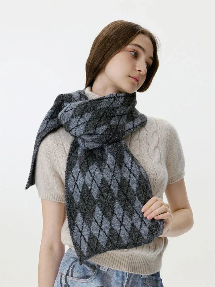 Woman touching her cream cable-knit sweater and a grey and black argyle scarf
