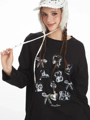 Close-up of a young woman's face and upper body. She is wearing a black long-sleeved graphic t-shirt with charms printed on it and a white polka dot bucket hat with fur trim. She is holding one of the hat's strings.