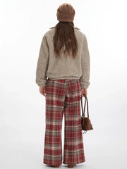 Back view of a model wearing a beige fuzzy bomber jacket with red plaid pants and a brown beanie.