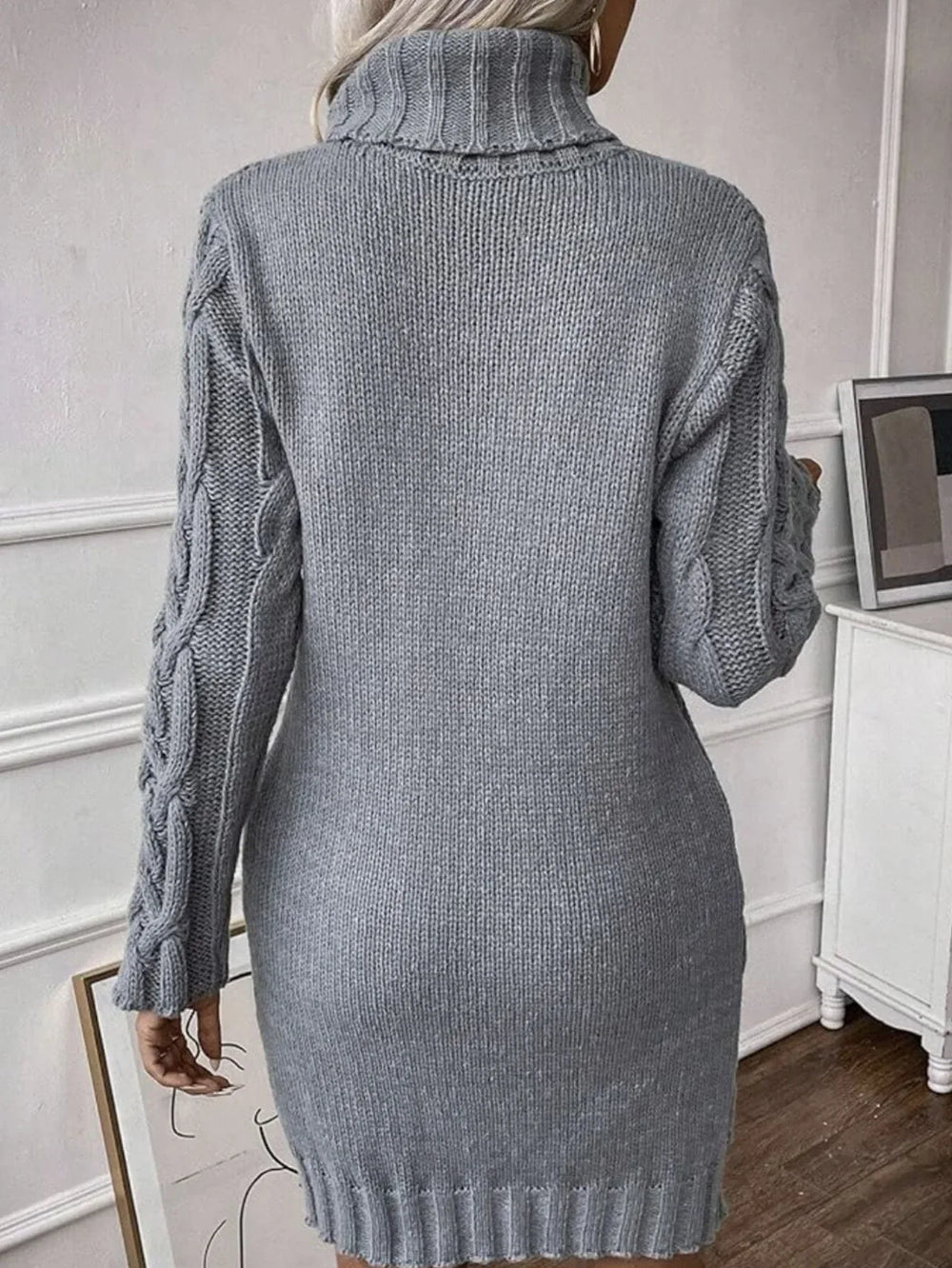 Back view of a woman wearing a grey cable knit turtleneck mini dress.