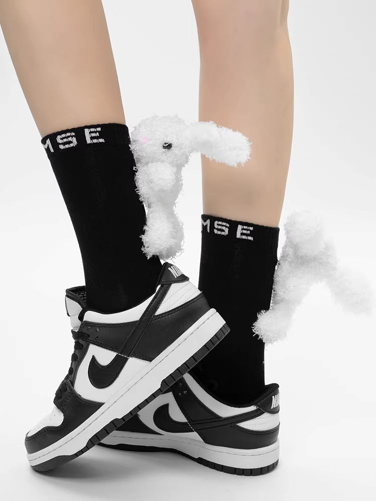Back view of black ankle socks with white 3D plush bunny embellishments and white sneakers