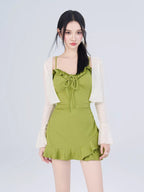 Front view of a woman modeling a green ruffled dress and white sheer cardigan