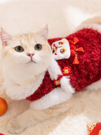 Close-up of a cream-colored cat wearing a red and white festive vest with a lion dance embellishment.