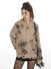 Close-up front view of a model wearing a distressed knit cardigan with a graphic print, focusing on the texture and pattern.