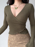 Woman wearing a green ribbed wrap top and a tan lace skirt, showcasing the wrap detail