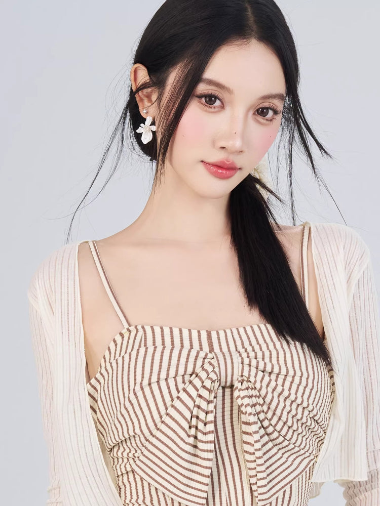 Close-up of a woman's face and upper body wearing a striped outfit and decorative earrings.