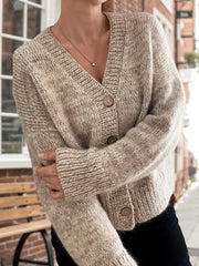 Close-up of a woman's chest area showing the details of a beige knit cardigan with buttons.