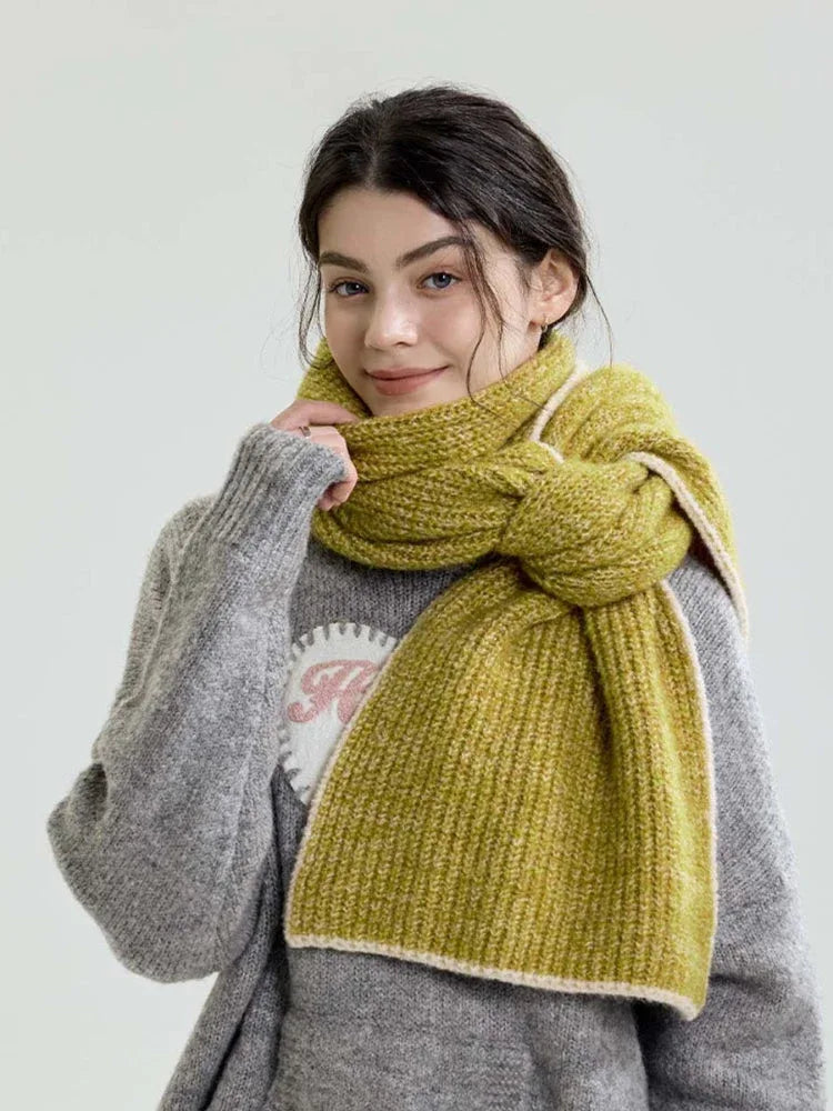 Model wearing a chunky knit scarf in a lime green hue, tied around the neck, over a grey sweater.