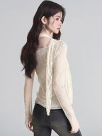 Rear view of a woman wearing a cream-colored sheer lace long-sleeve top with a scarf detail.