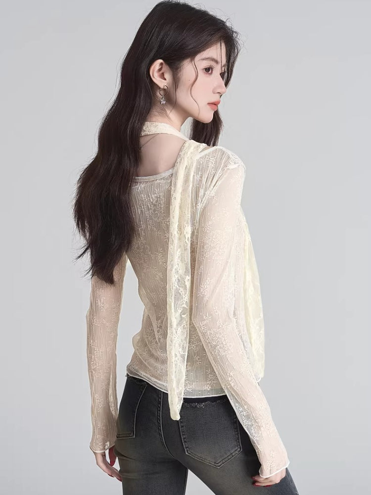 Rear view of a woman wearing a cream-colored sheer lace long-sleeve top with a scarf detail.