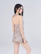 Woman modeling a plaid halter dress from the back