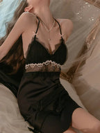 Woman posing in a black satin babydoll nightgown with lace trim.