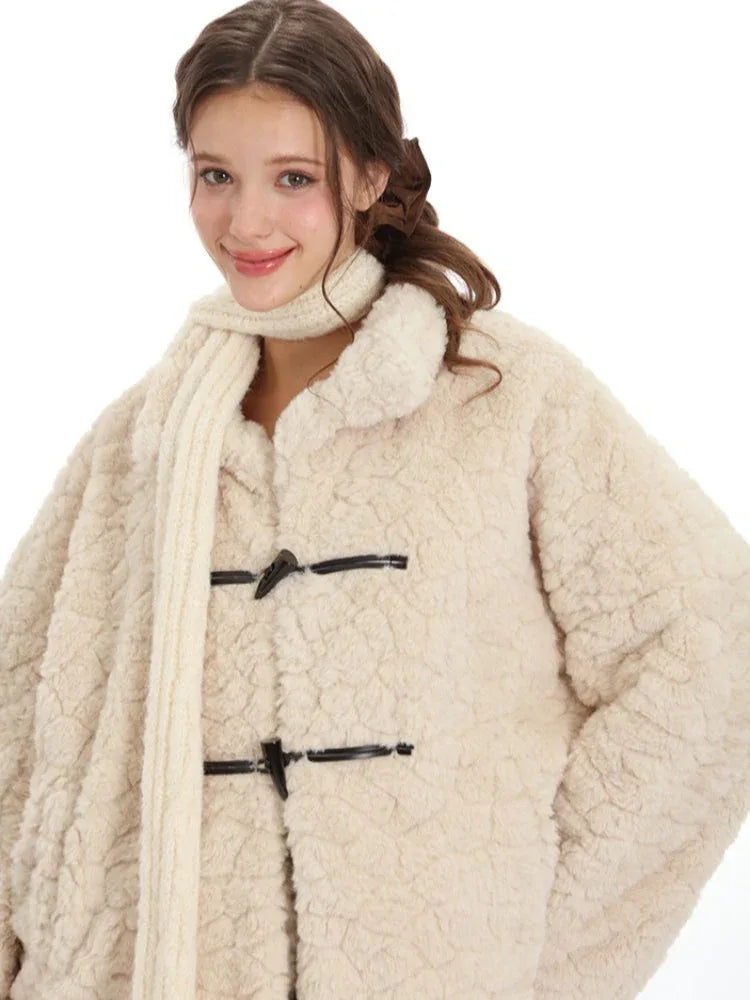 Close-up of a woman's face and upper body wearing a cream-colored fleece coat with toggle closures and a cream scarf.