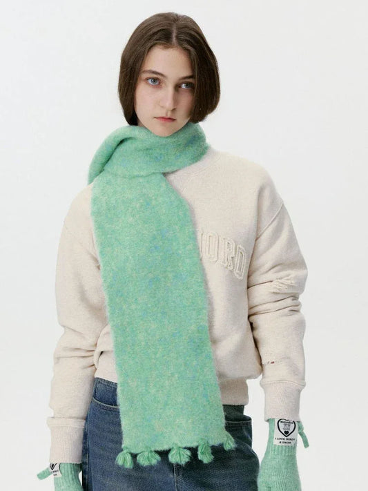 Model wearing a mint green fuzzy scarf with tassels