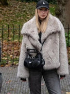 Woman wearing a light grey oversized faux fur jacket with black jeans and a black handbag