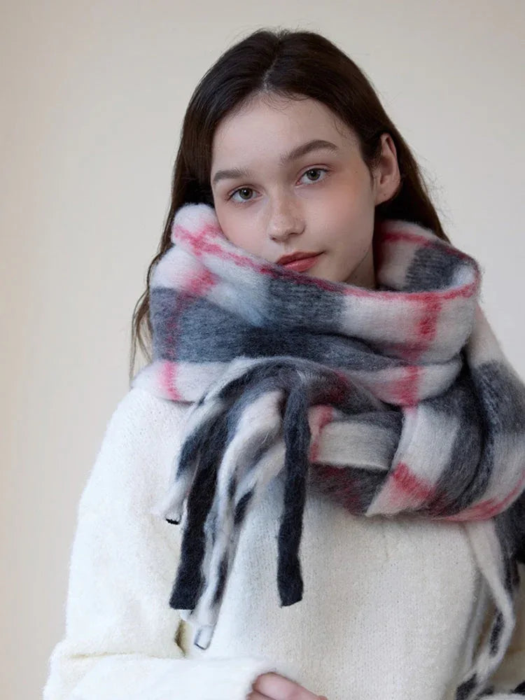 Close-up of a woman wearing a cream-colored sweater and a fuzzy plaid scarf around her neck.