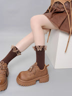 Side view of brown ribbed socks with ruffled butterfly trim and brown lace-up platform shoes.