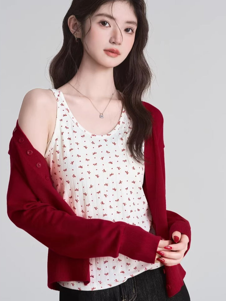 Woman with her red cardigan draped off one shoulder, revealing a floral tank top.
