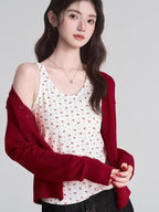 Woman with her red cardigan draped off one shoulder, revealing a floral tank top.