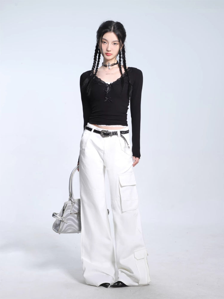 Full-body shot of a model in a black ribbed long-sleeve top, white cargo pants, and a silver handbag.