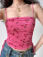 Front view of a pink mesh crop top with a cherry print, showing the square neckline and ruched sides.