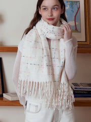 Woman adjusting a white plaid scarf with fringe detail