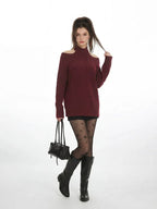 Full-body shot of a model in a maroon open-shoulder sweater, black shorts, star tights, and black boots.