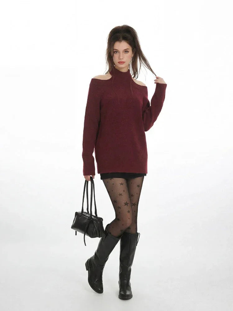 Full-body shot of a model in a maroon open-shoulder sweater, black shorts, star tights, and black boots.