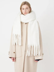 Woman wearing a white fluffy scarf draped over a beige coat, front view