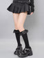 Model wearing black knee-high socks with lace trim and heart charms, a black pleated mini skirt, and black buckled platform shoes.