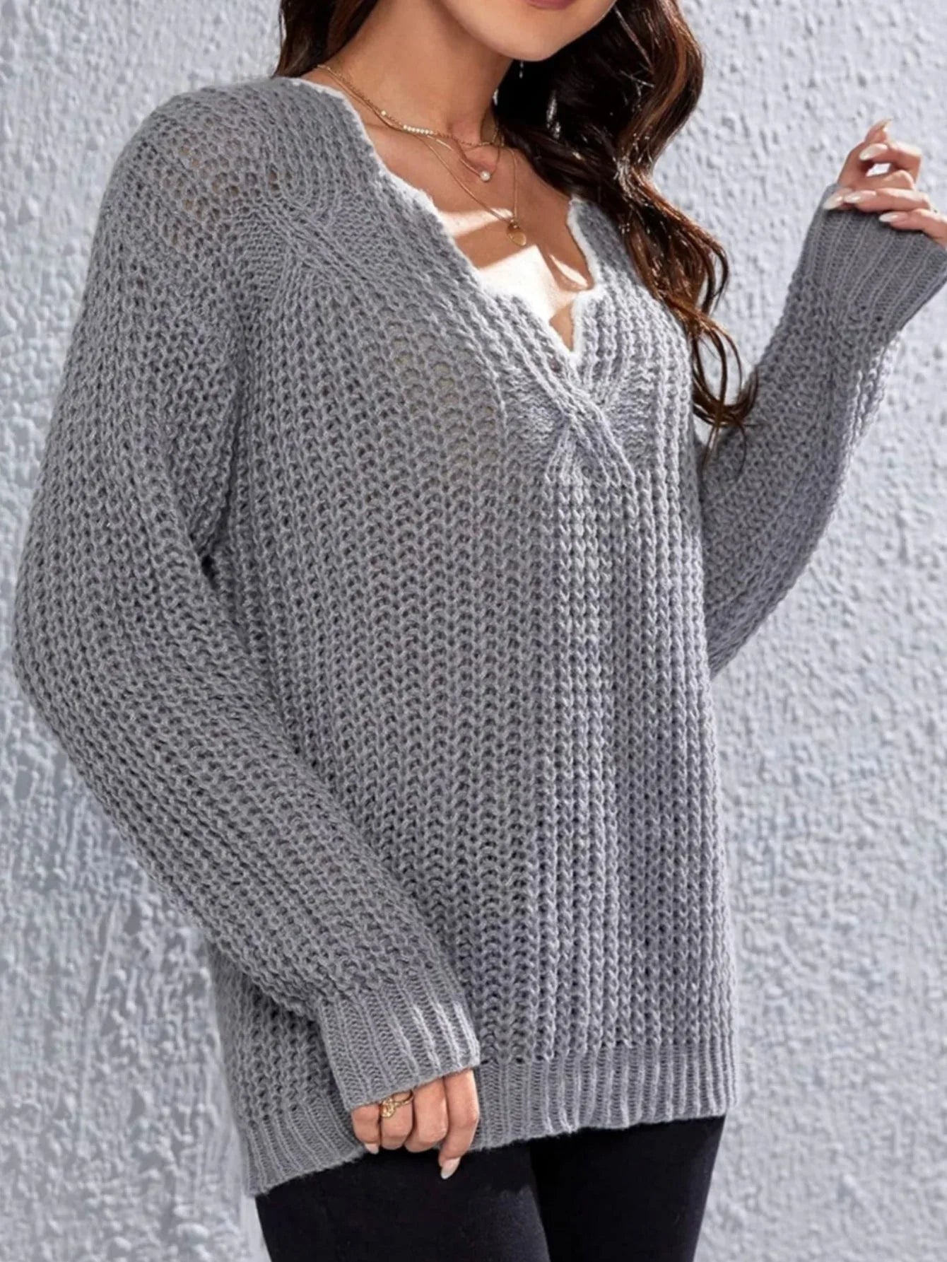 Woman wearing a grey knit V-neck sweater with long sleeves