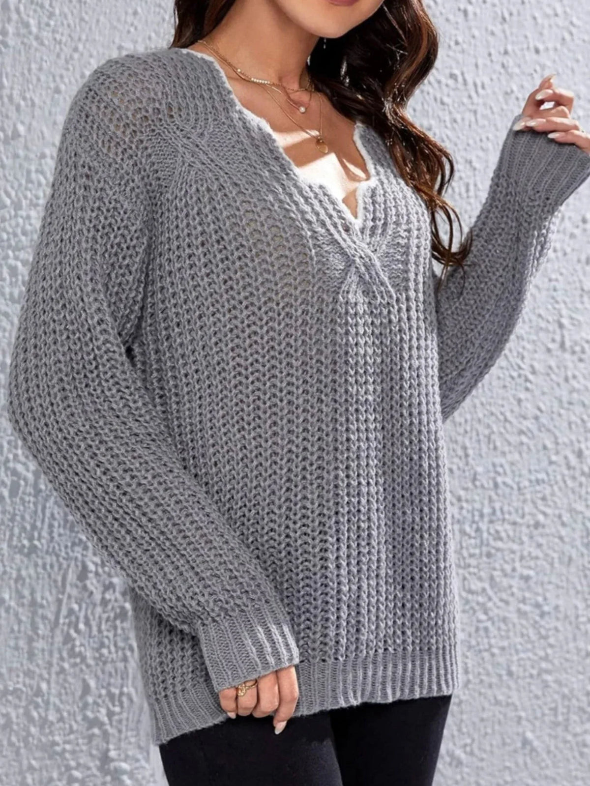 Woman wearing a grey knit V-neck sweater with long sleeves