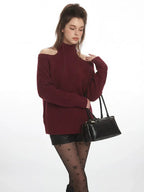 Model posing with a black handbag, wearing a maroon open-shoulder sweater and star-patterned tights.
