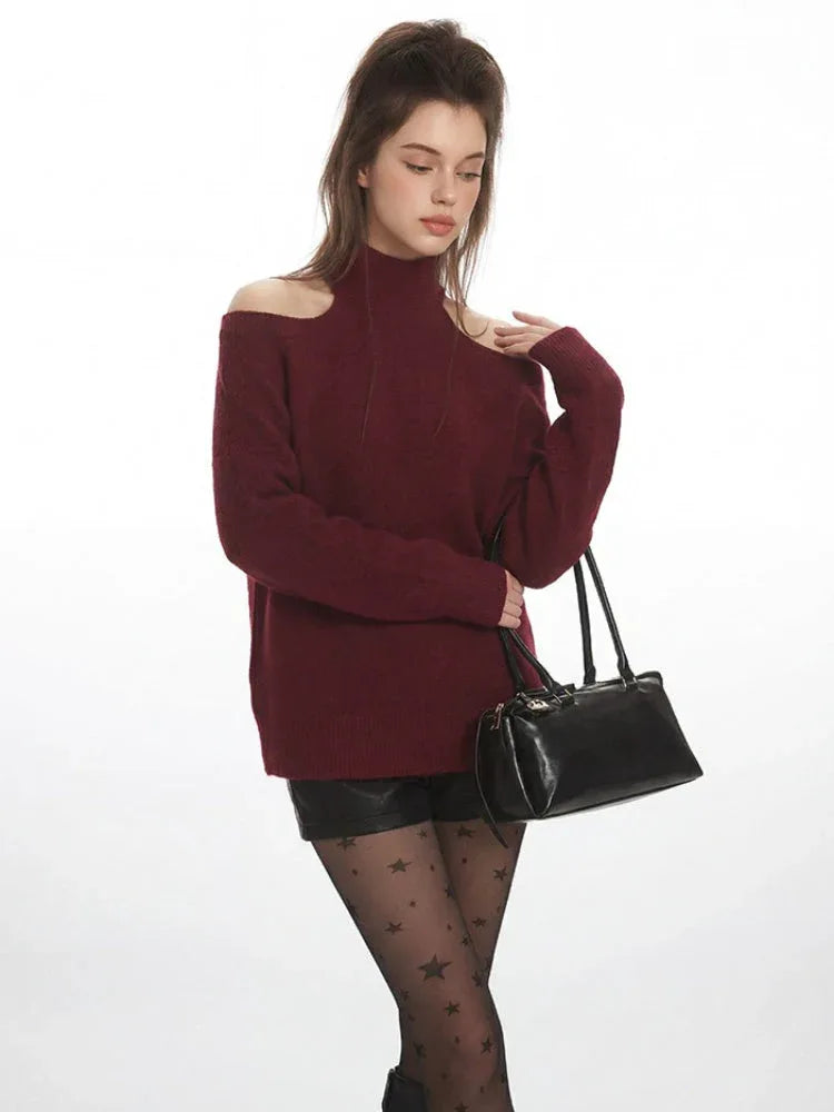 Model posing with a black handbag, wearing a maroon open-shoulder sweater and star-patterned tights.