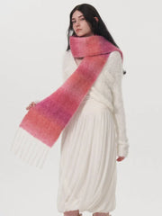 Woman wearing a white dress and a pink and orange gradient scarf with fringe detail.
