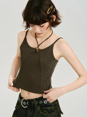Woman wearing a dark olive green halter crop top with a ring detail at the neckline, pulling at the hem.