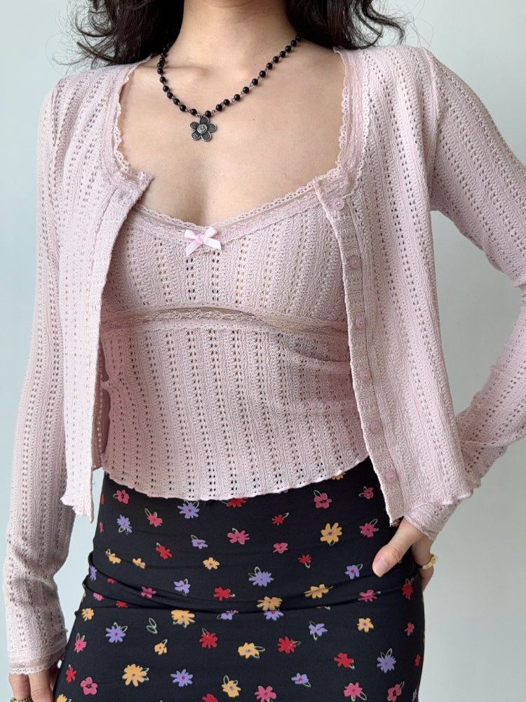 Woman wearing a pink cropped knit cardigan with lace trim and a floral print skirt, showing the full outfit.
