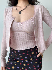 Woman wearing a pink cropped knit cardigan with lace trim and a floral print skirt, showing the full outfit.
