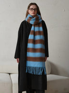 Full-body view of a woman in a black coat and a blue and brown striped scarf