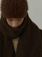 Close-up of a model wearing a brown fuzzy hat and scarf