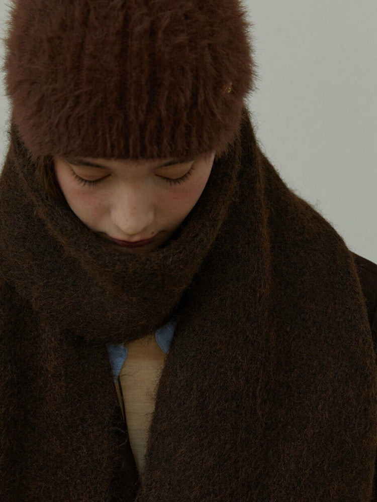 Close-up of a model wearing a brown fuzzy hat and scarf