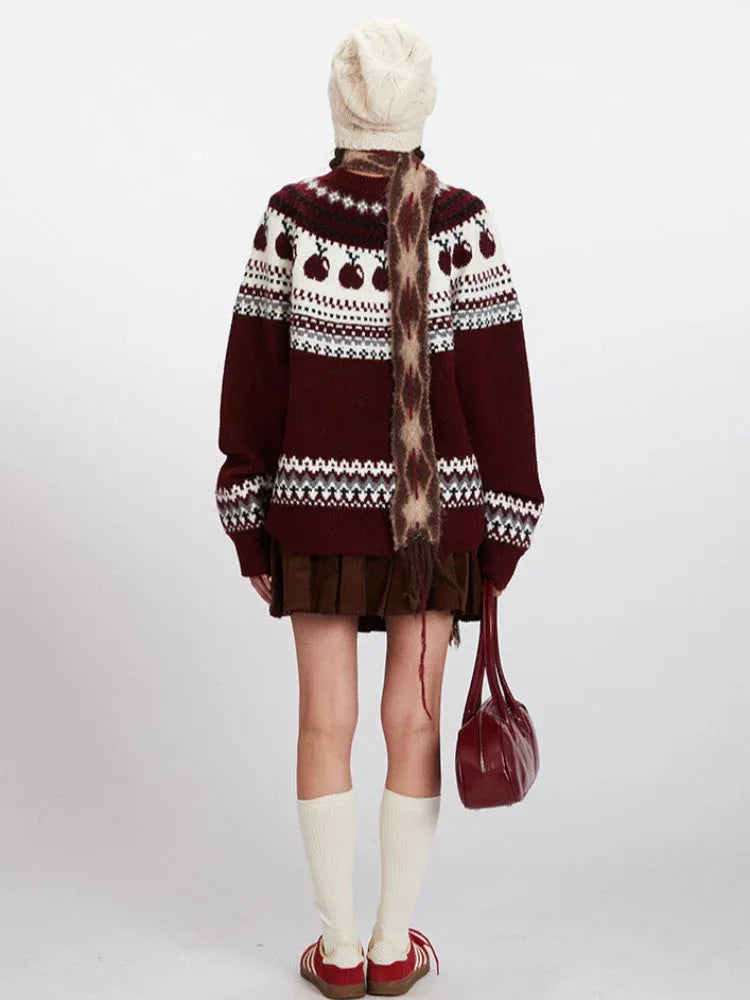 Back view of a woman wearing a maroon and white knit sweater with an apple Fair Isle pattern, brown corduroy skirt, white beanie, patterned scarf, white socks, and red sneakers. Secondary image