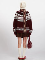 Back view of a woman wearing a maroon and white knit sweater with an apple Fair Isle pattern, brown corduroy skirt, white beanie, patterned scarf, white socks, and red sneakers.