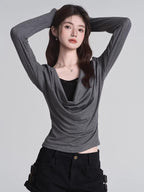 Model wearing a grey long-sleeved top with a draped neckline and a black underlayer.